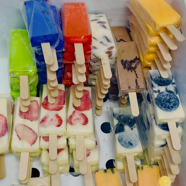 Assorted paletas, including strawberry, Oreo, mango, and other fruit flavors, in a cooler.