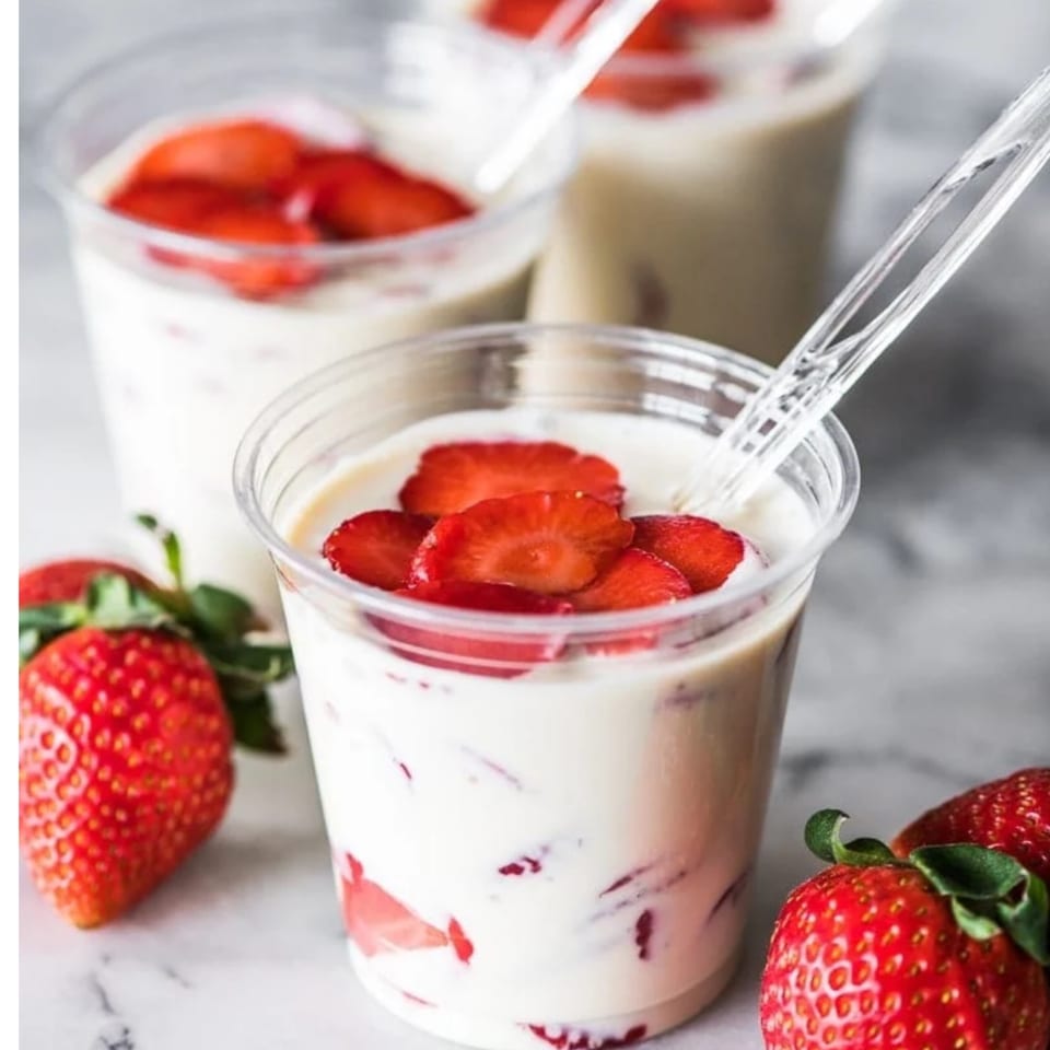 Three cups of fresas con crema, a Mexican dessert, with fresh strawberries and spoons.